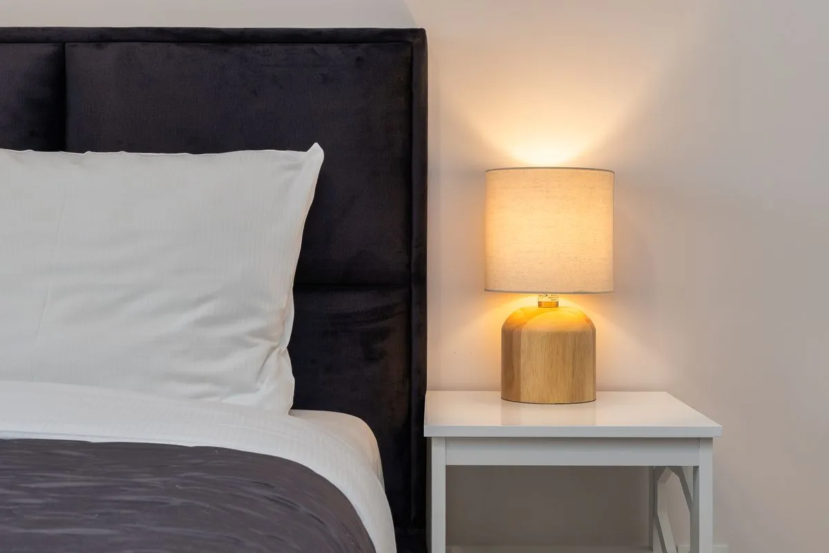 A bedside lamp lights a quiet bedroom at night