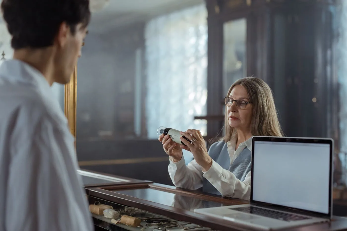 A pharmacist talks with an older customer at the counter